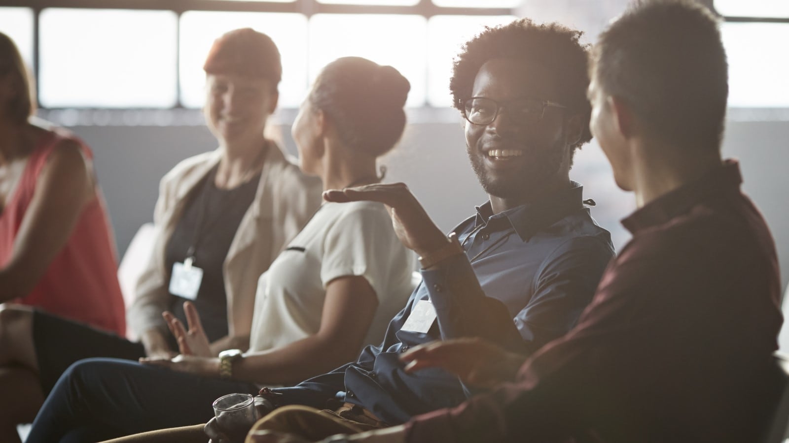 People in a room sitting and speaking with each other.