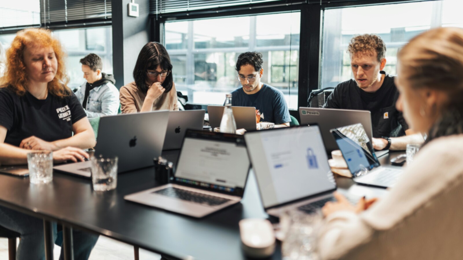 Rühm kolleege ümber töölaua arvutite taga arutamas