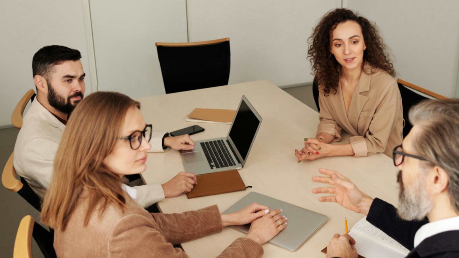 Neli kolleegi koos töötamas telefonide ja arvutitega