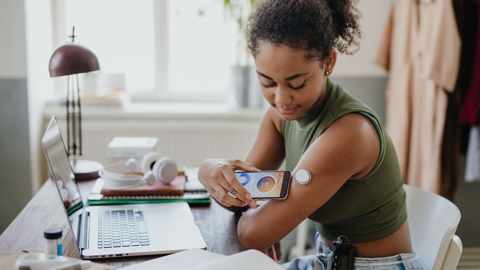 Young woman scanning a glucose monitor on her arm with a smartphone at home.