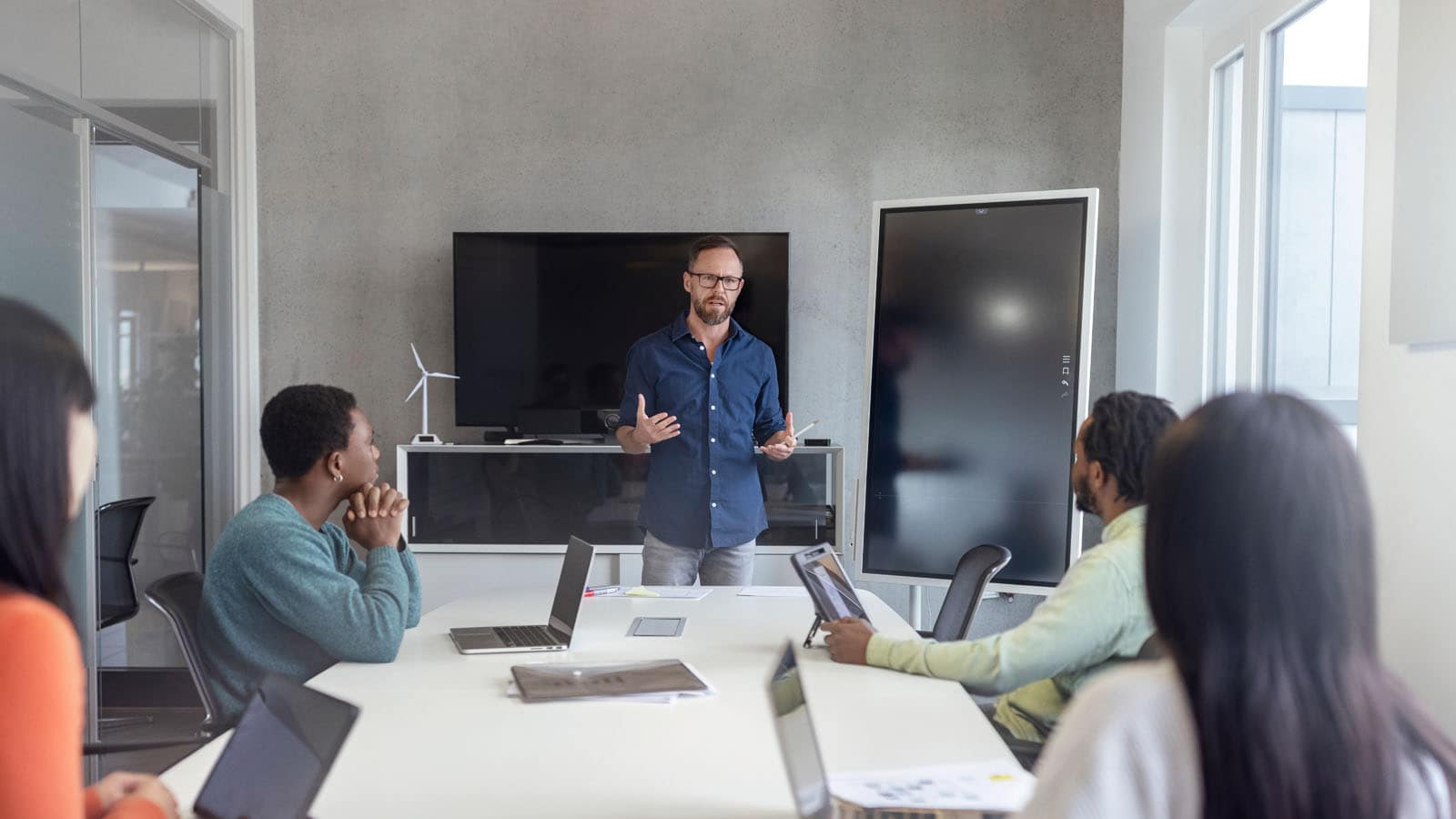 Manager presents his ideas in front of large monitors