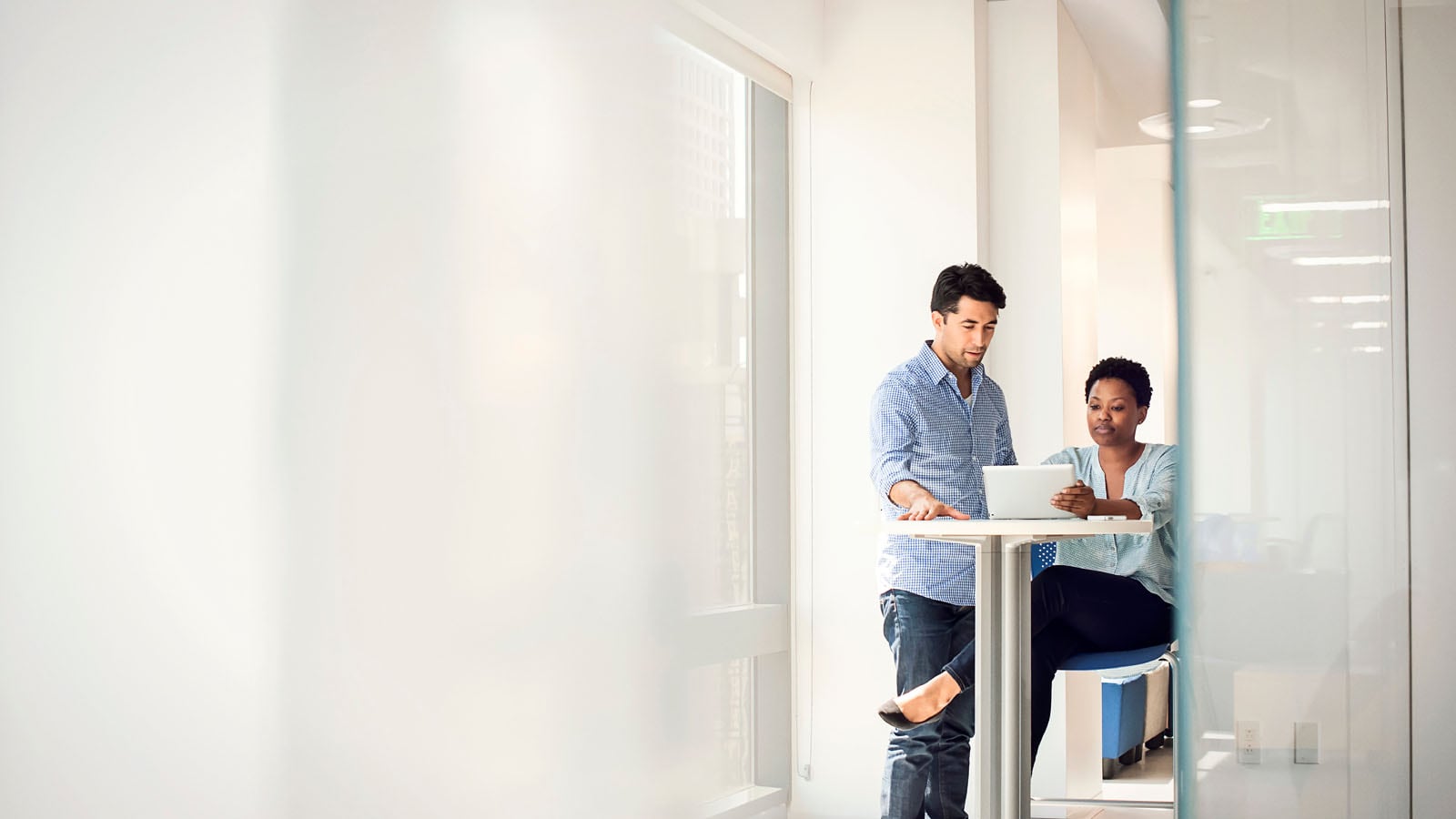 Two colleagues looking at digital tablet in a bright workspace