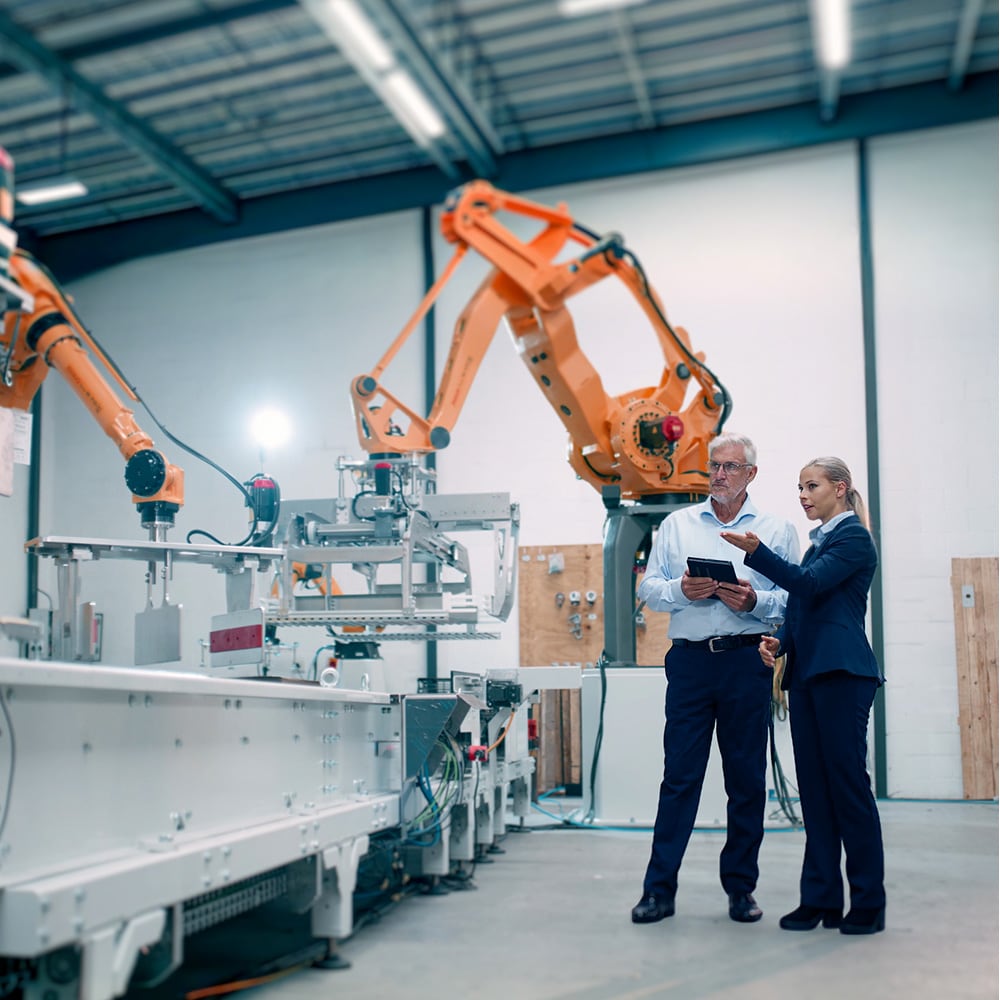 Man och kvinna studerar robotar i arbete.