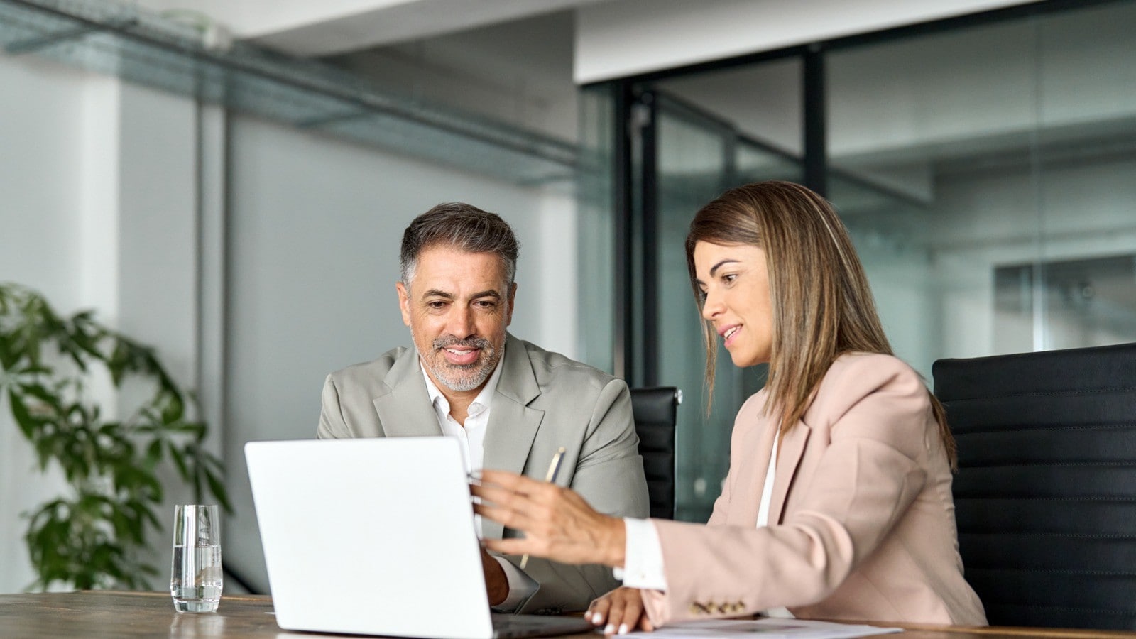 A man and a woman talking infront of a laptop in an office environment 