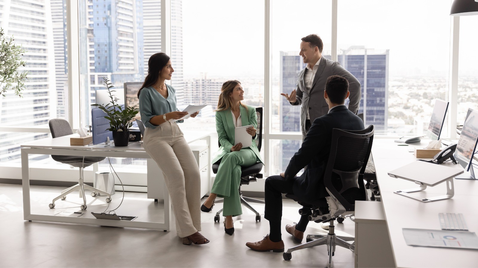 People collaborating in a bright modern office meeting area with city views.