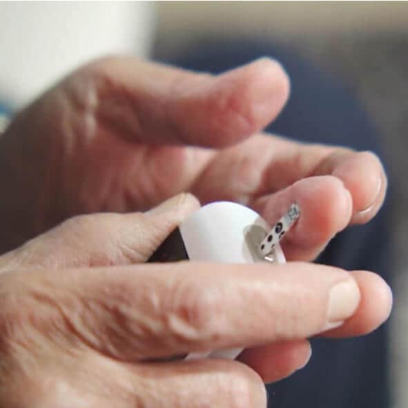 Close-up of a person holding and using a blood glucose monitor