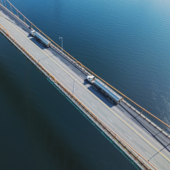 Two semi-trucks haul bulk commodity trailers on an over-water highway