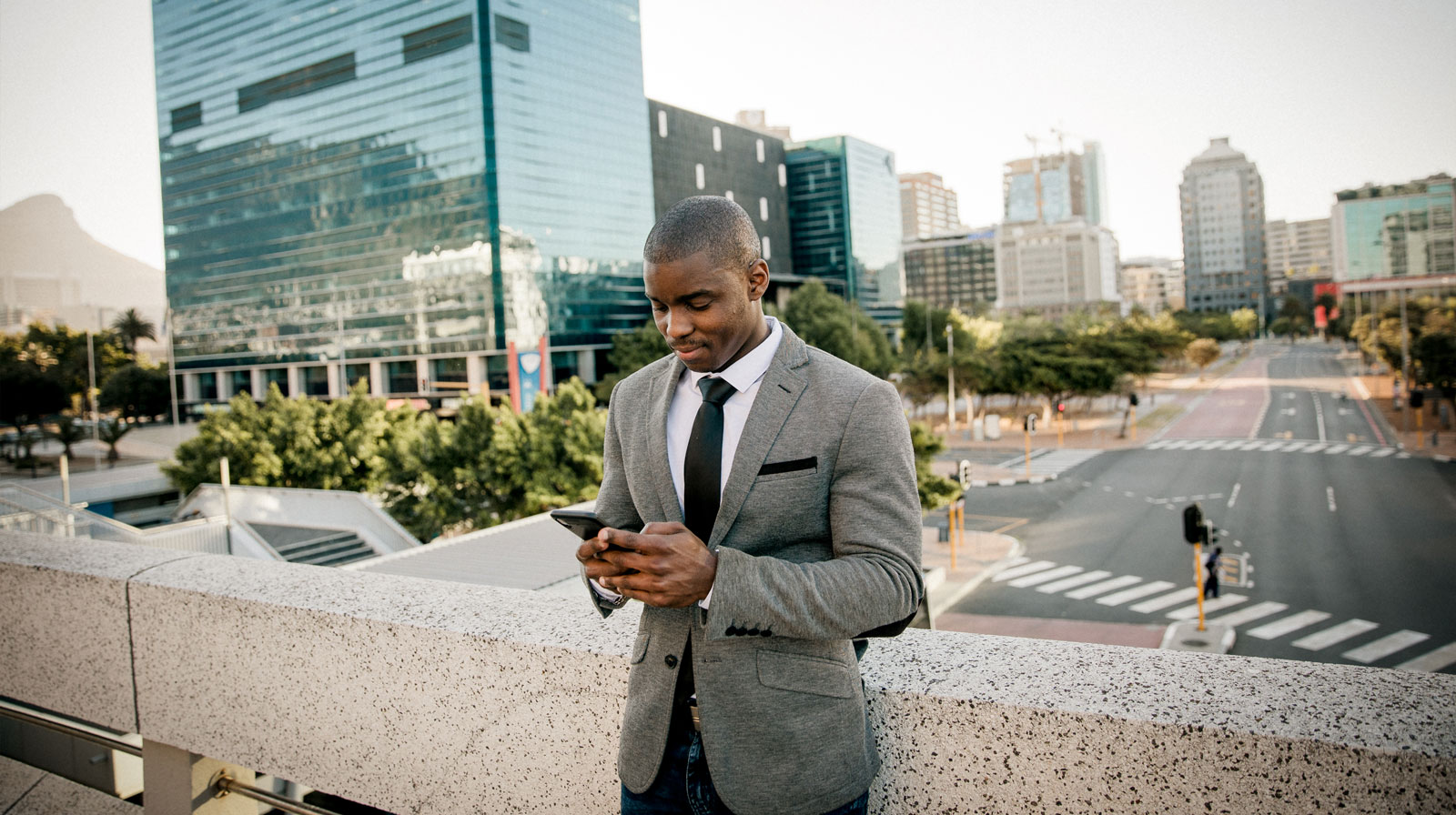 Businessman reading his phone with cityscape behind him