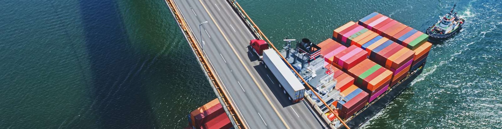 smagā automašīna šķērso tiltu, zem tā kravu ved kuģis