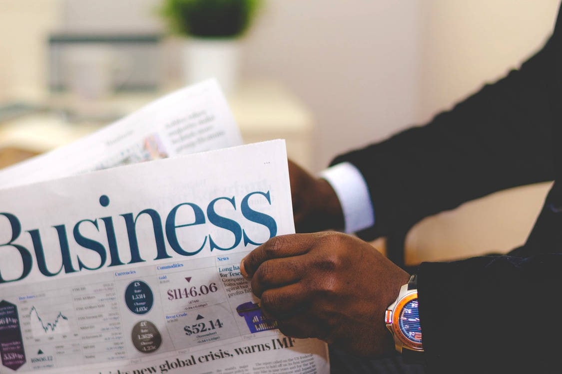 a person holding and reading a business newspaper
