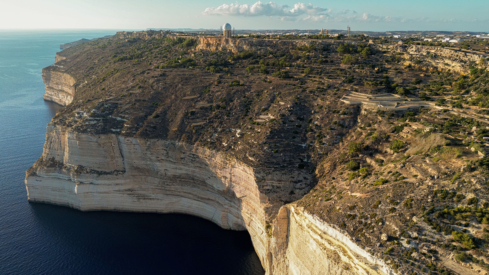  a landscape of  steep limestone cliffs that drop sharply into a deep blue sea