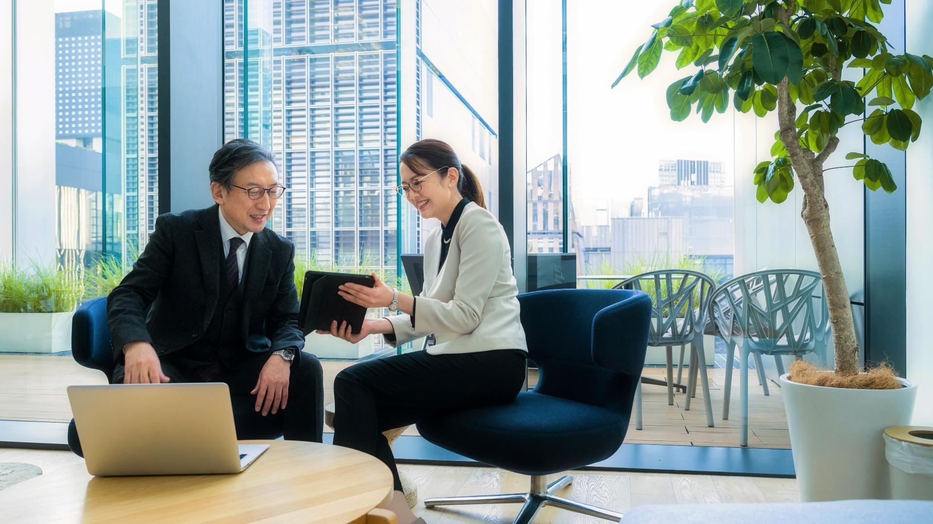 Businesswoman showing colleague data on a digital tablet while working in office