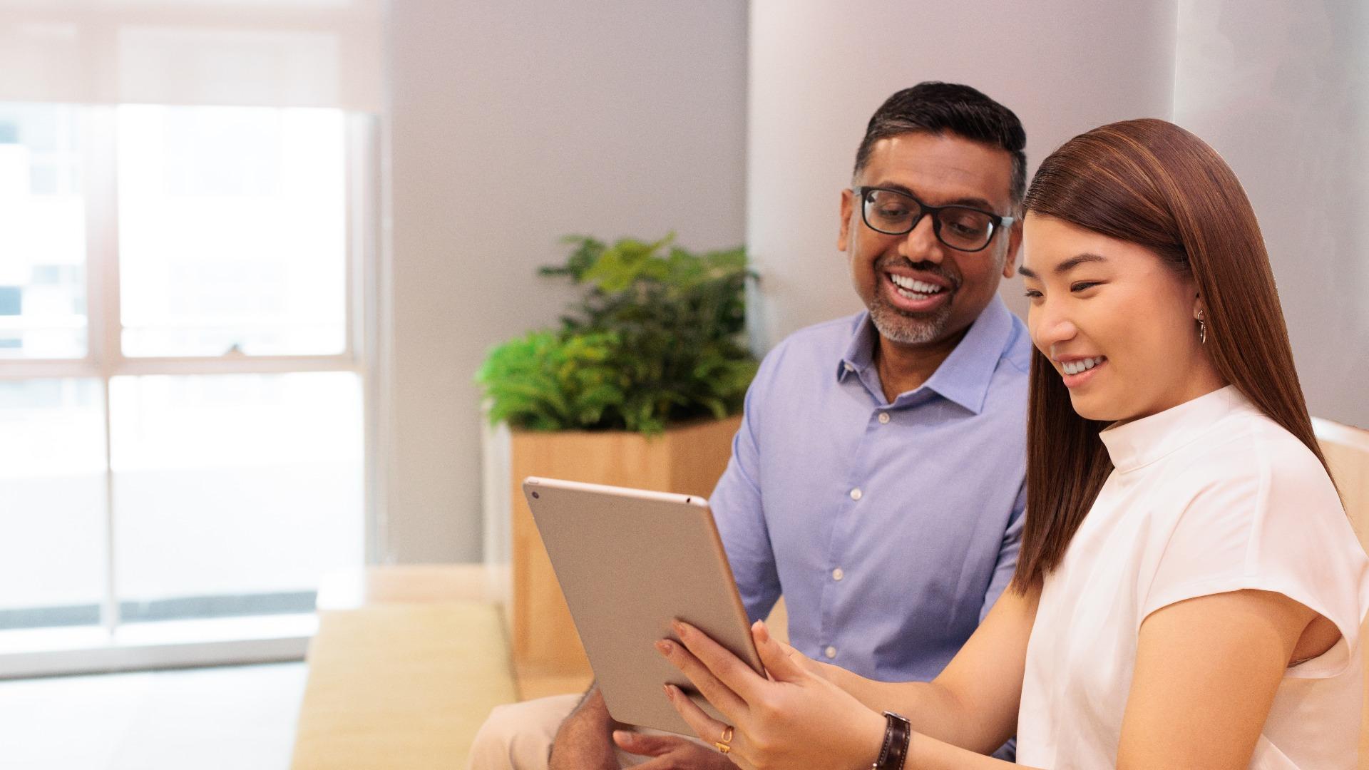 Business colleagues smiling and viewing a digital tablet