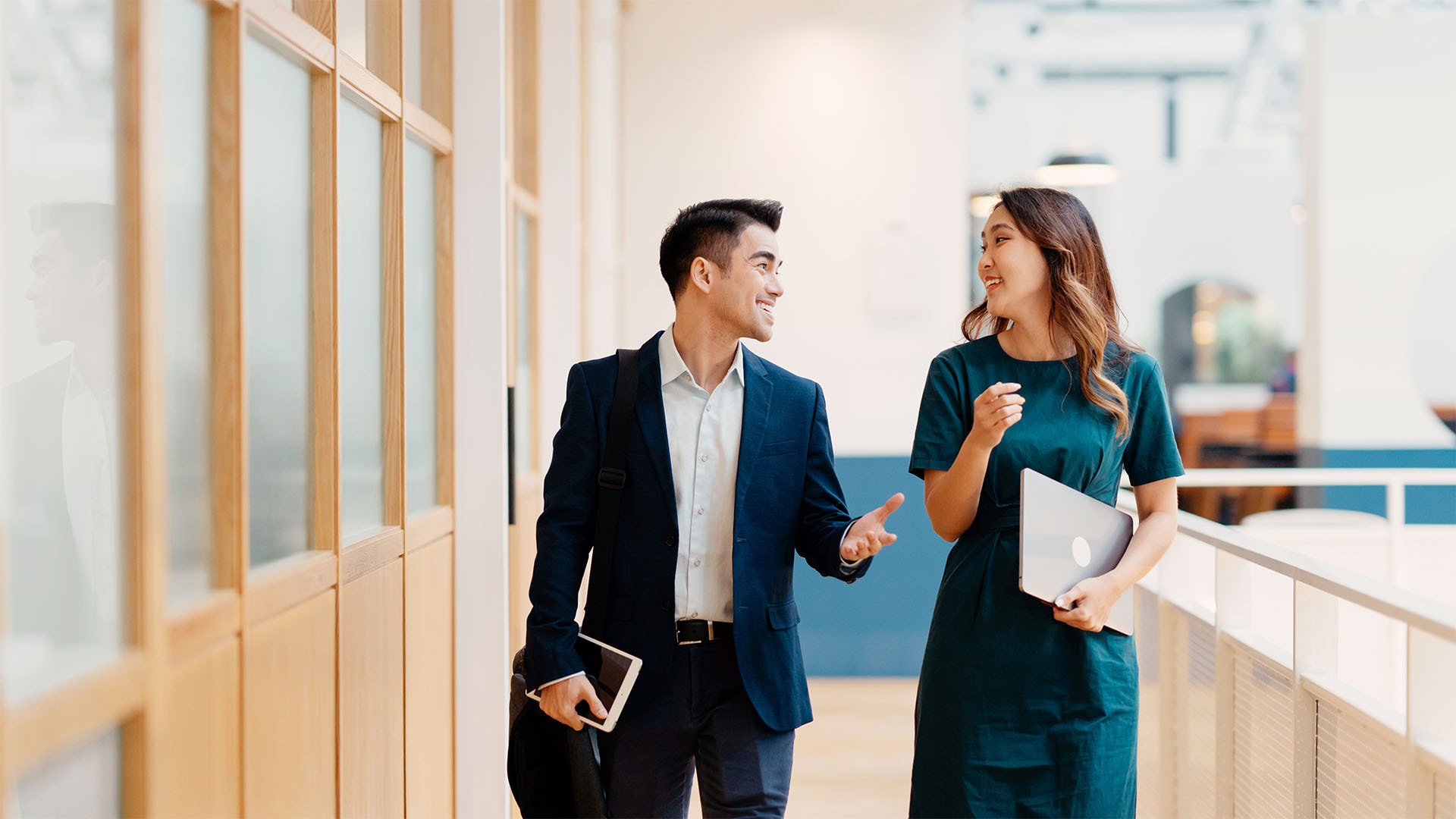 Businessman and businesswoman discussing business strategy while walking in an office corridor