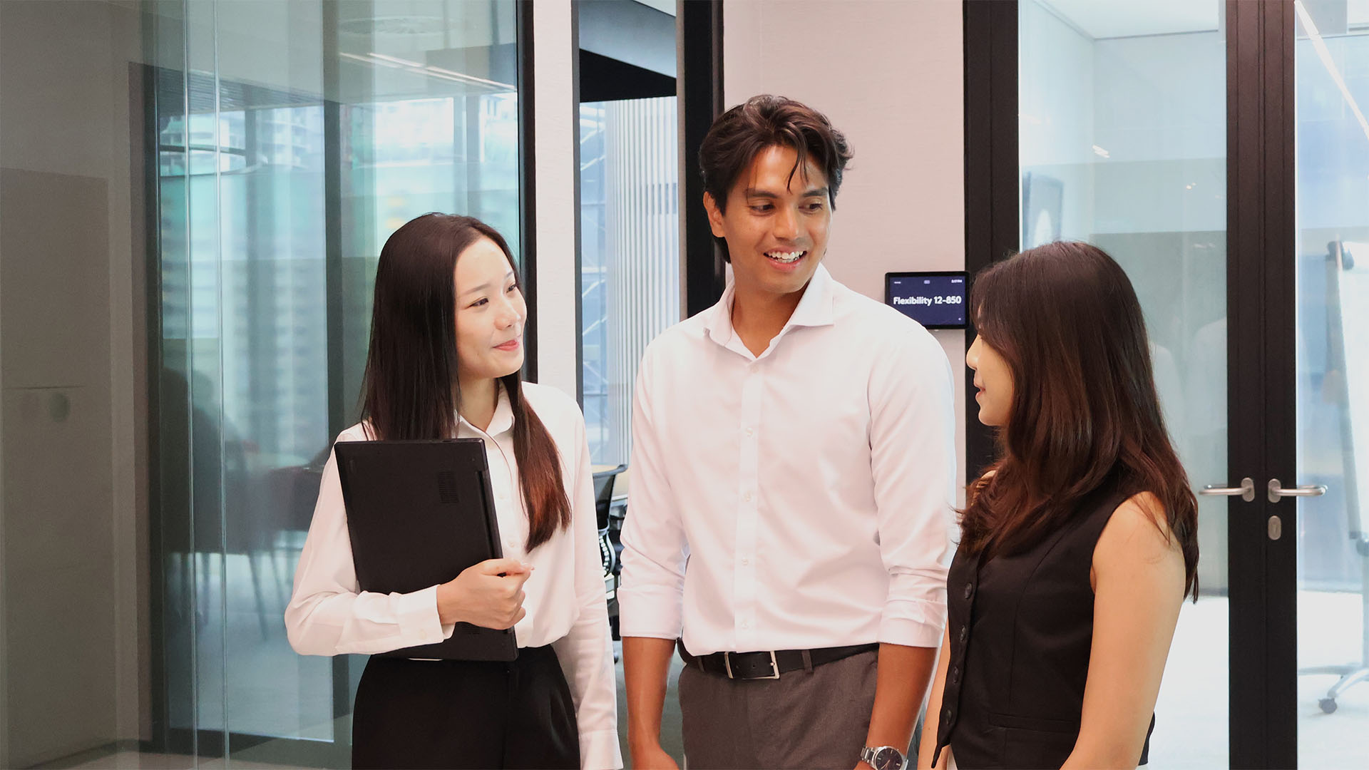 Three colleagues having a discussion at a office corridor