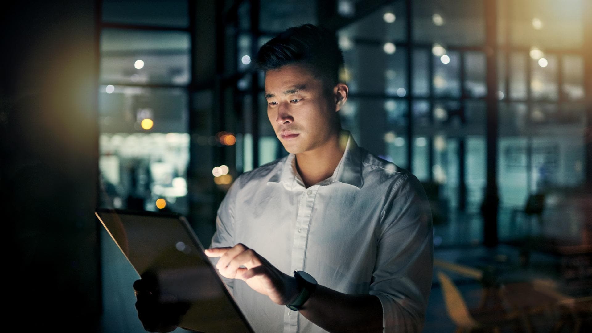 Young businessman using a digital tablet during a late night in a modern office