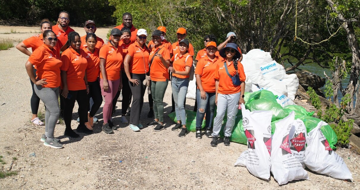 group of volunteers standing on the beach with bags of garbage they collected
