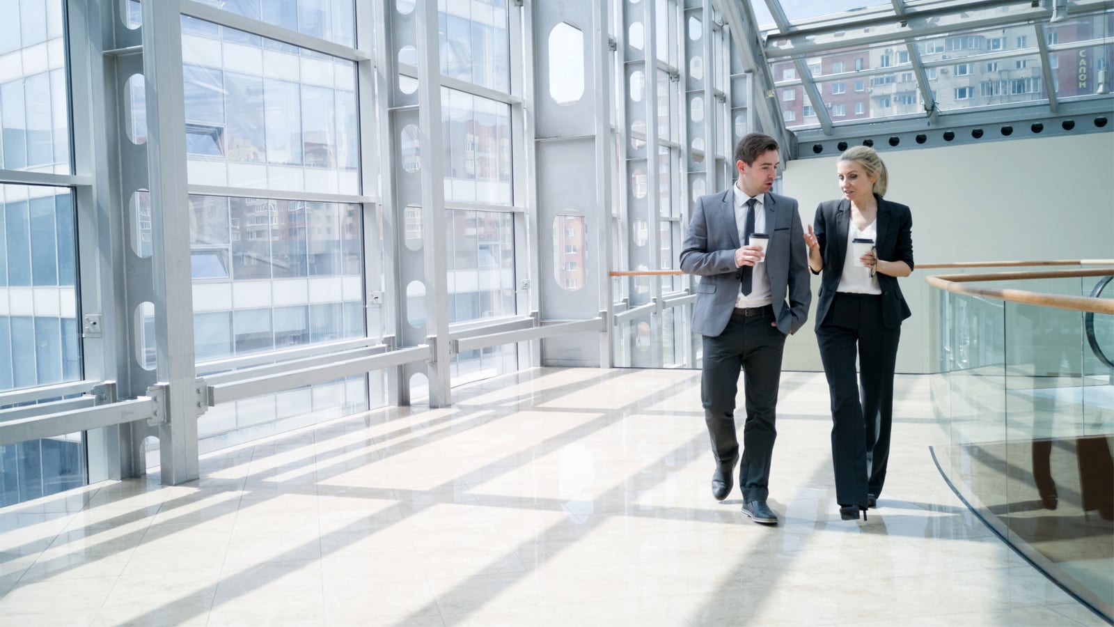 2 people walking in a glass office buiding