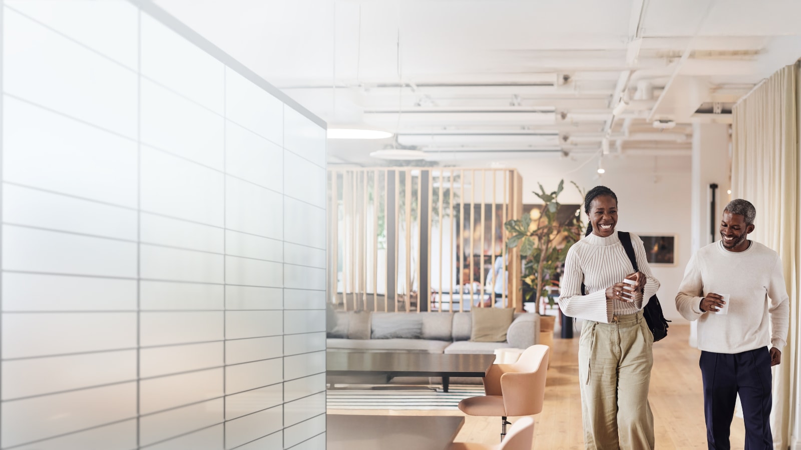 two people walking in a bright office