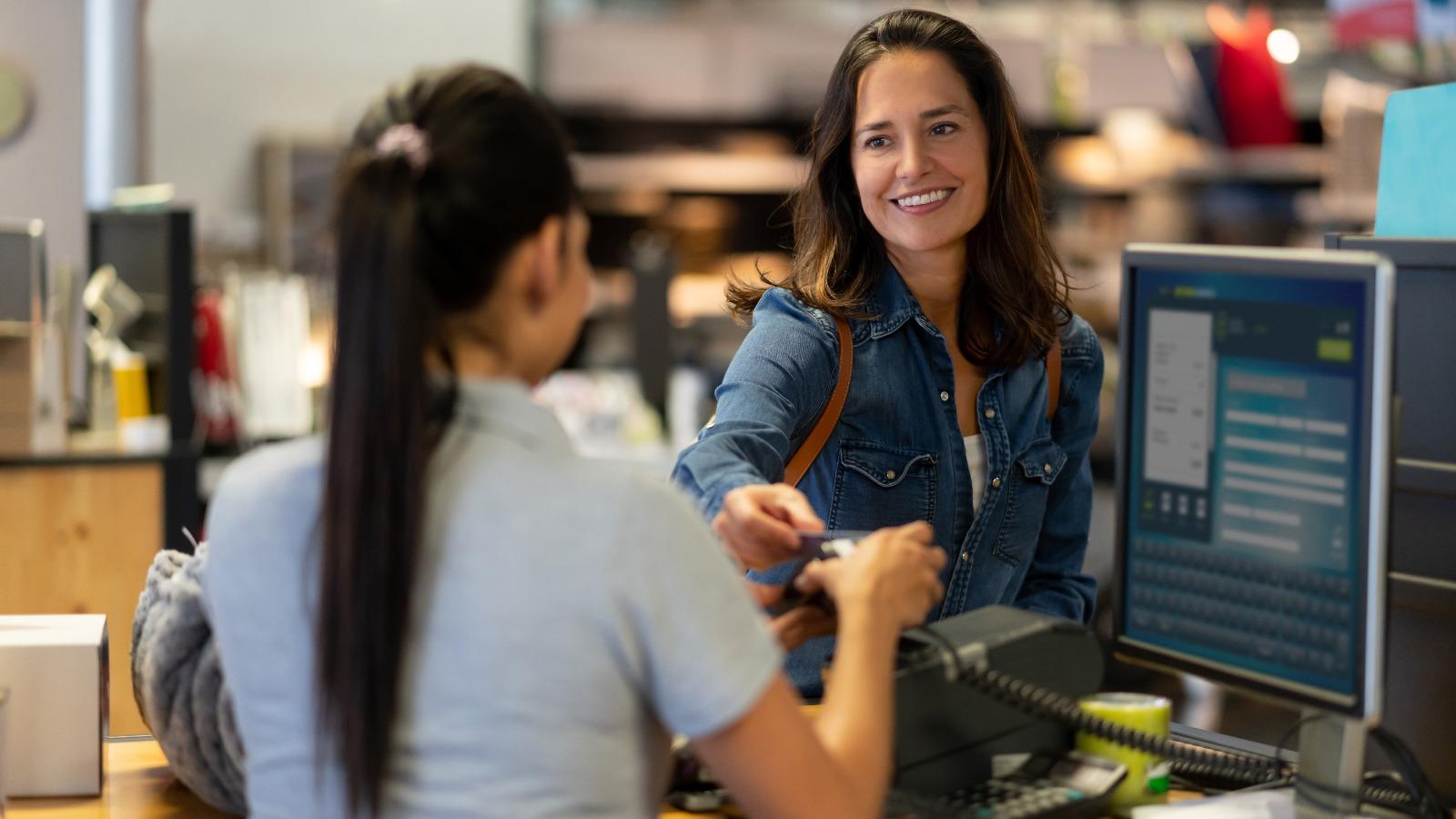 Cheerful customer making a contactless payment with credit card at a furniture store