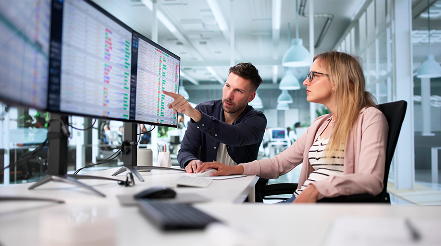 2 people looking at multiple computer screens